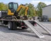 Stationary flatbed delivery truck with excavator and lowered loading ramps — generated illustration