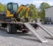Stationary flatbed delivery truck with excavator and lowered loading ramps — generated illustration