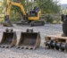 Generic excavator buckets and auger arranged in an outdoor equipment yard — generated illustration