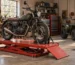 Motorcycle secured on a service lift table with ATV parked in workshop — generated illustration